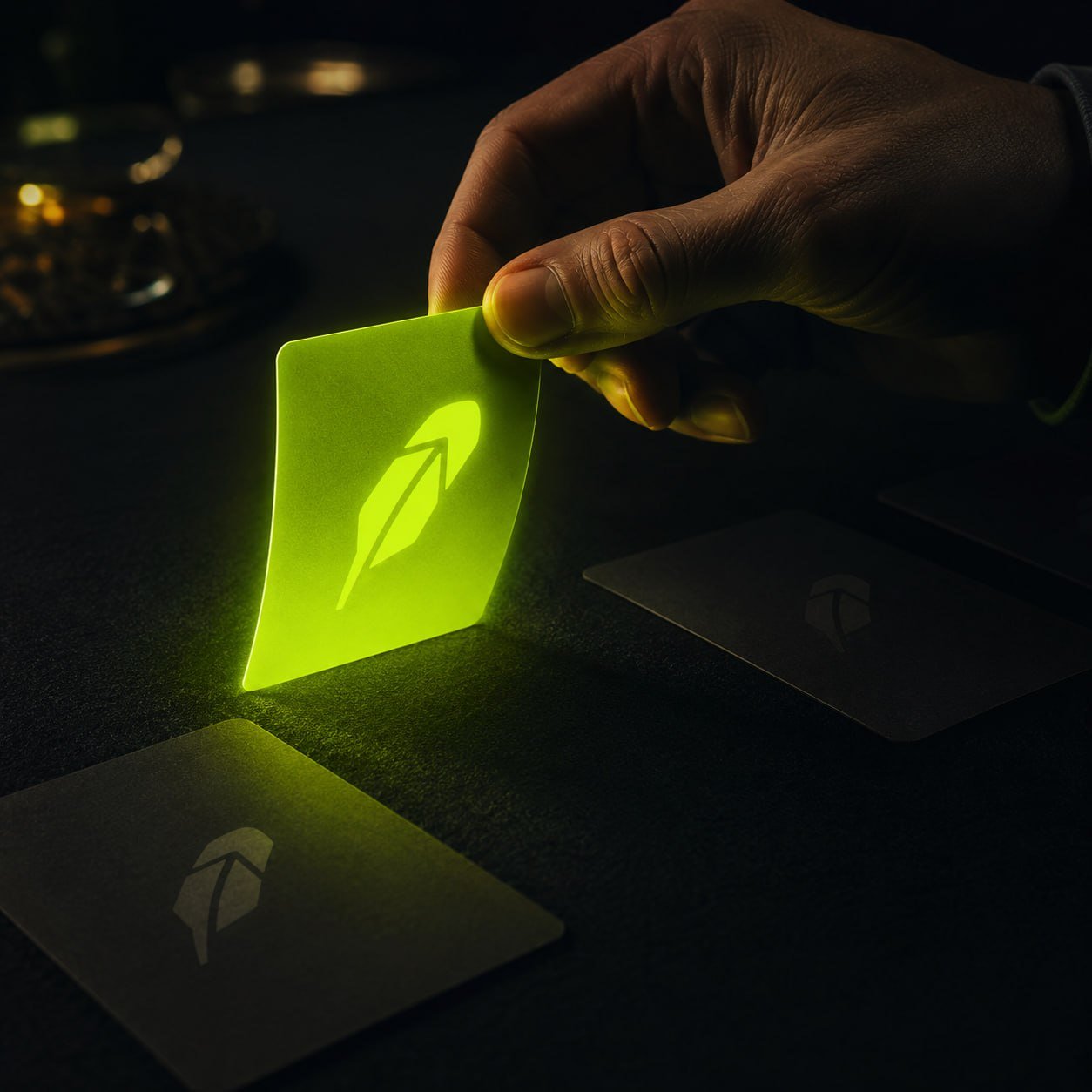 Glowing neon Robinhood card held in the dark